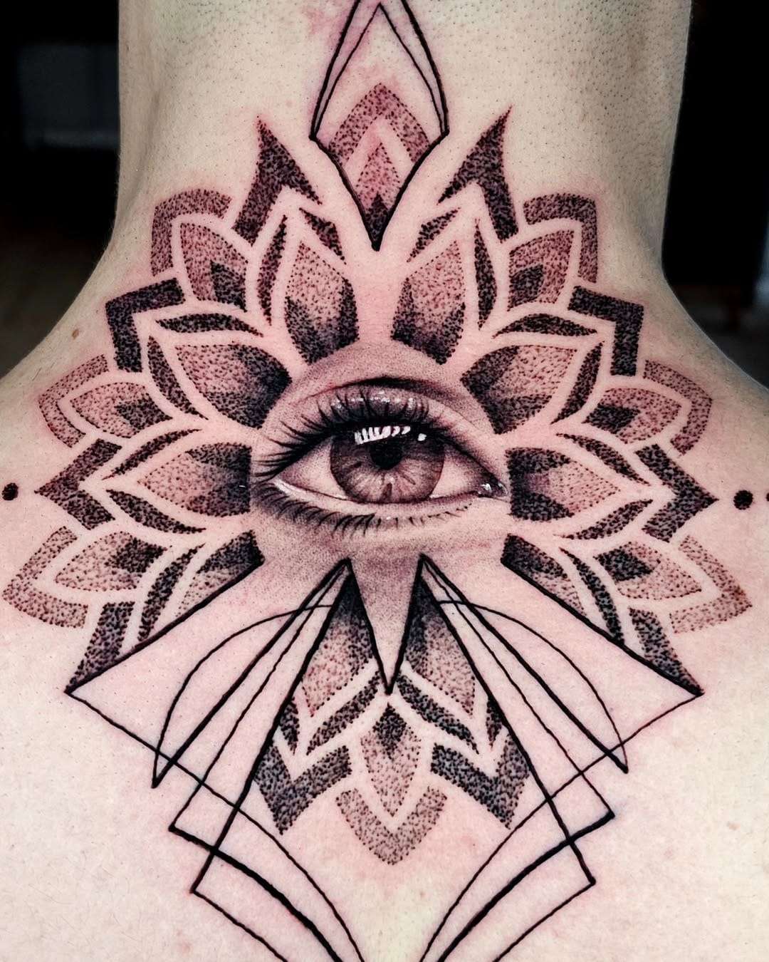 Mandala em pontilhismo nas costas, com um olho realista no centro